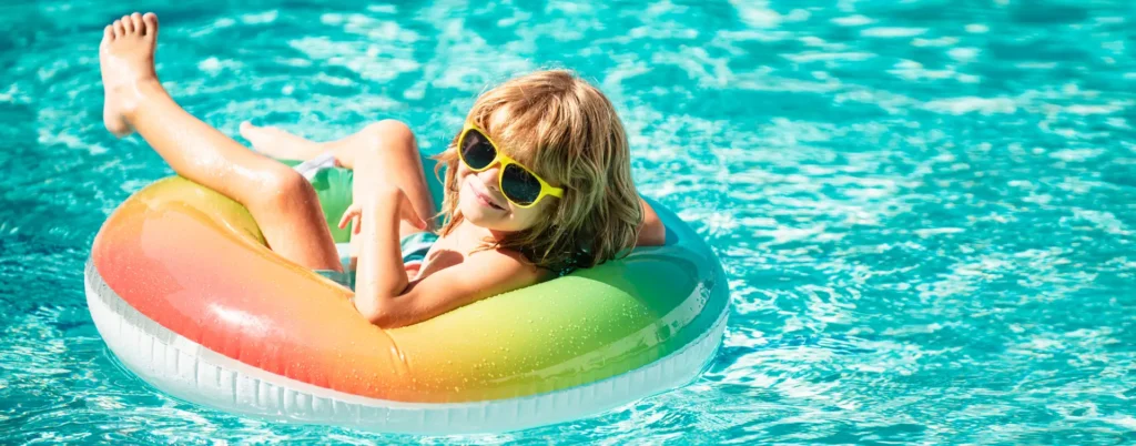 A kid having fun in a donut float in a beautiful Miami residential pool under the bright