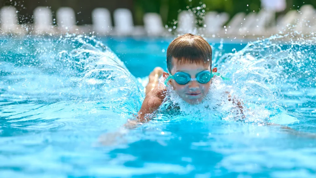 Happy kid in a sparkling pool maintained by Amenity Pool Services