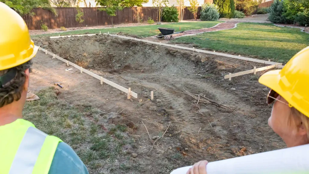 Mid-construction scene of an in-ground swimming pool, showing the excavated hole