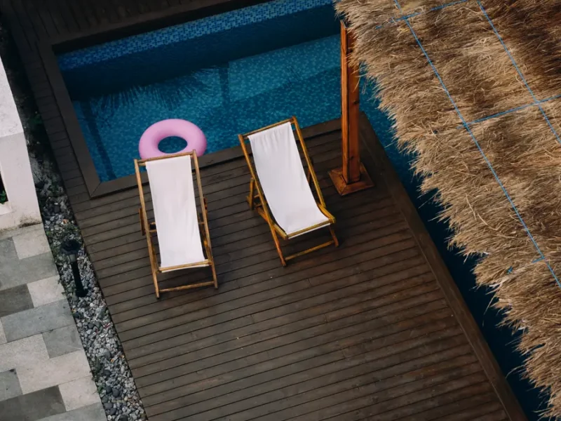Aerial view of two lounge chairs in commercial pool area with peaceful blue water vibe